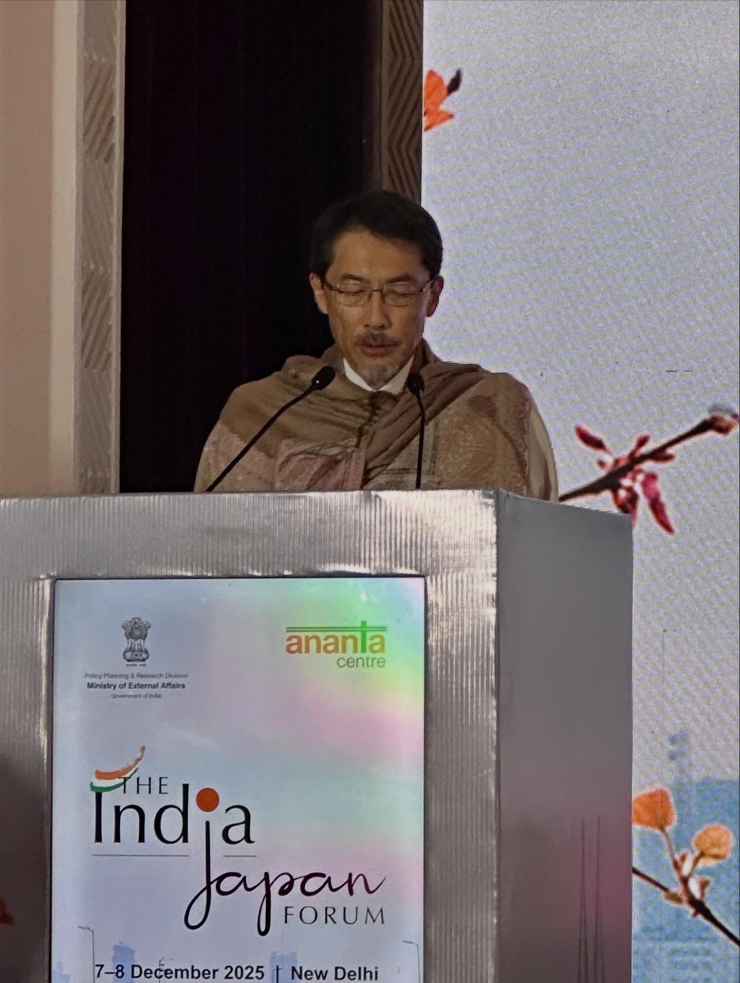 ‎演壇、‎、「‎ب Dheice enal AMtaira ananla la centre Indja Indja TTHE ι Joyan FORUM 7-8 December 2025 t New Delhi‎」というテキスト‎‎の画像のようです